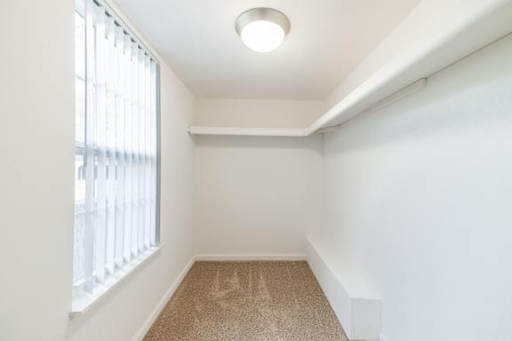 A room with a carpeted floor and a window with blinds.
