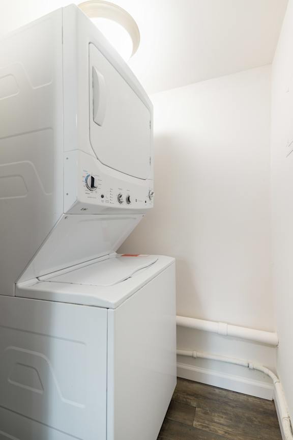 A white dryer is sitting in a room with a white wall.