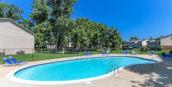 A large swimming pool surrounded by trees and chairs.