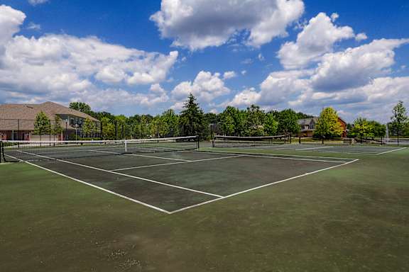 A tennis court surrounded by trees and a building.
