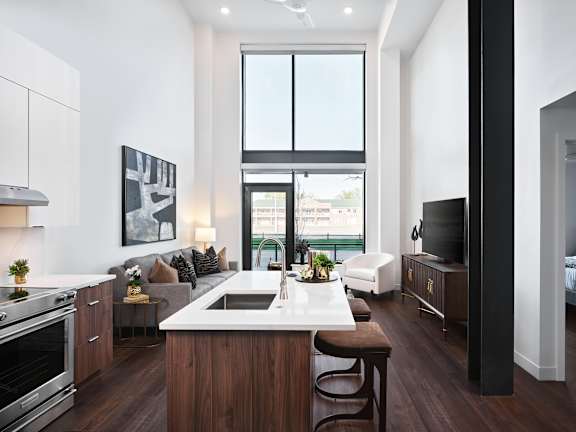 A modern kitchen with dark wood floors and white countertops.
