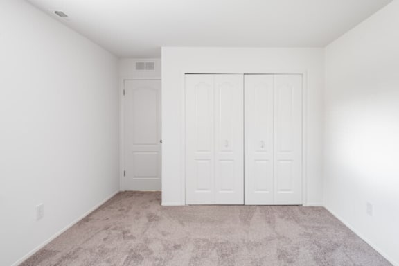 an empty room with white walls and doors and carpet