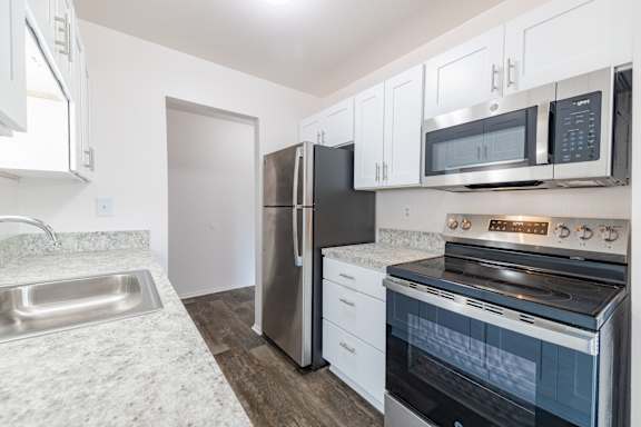 A kitchen with a stainless steel refrigerator, oven, and microwave.