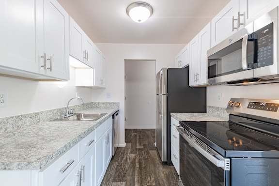 A kitchen with white cabinets and a black refrigerator.