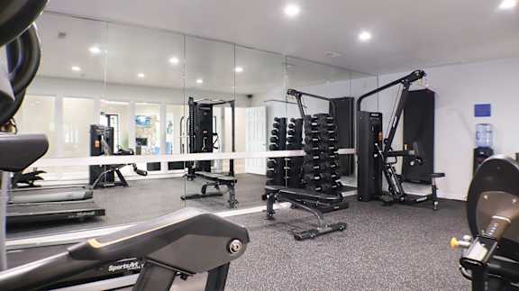 A gym with a variety of equipment including treadmills, weights, and exercise machines.