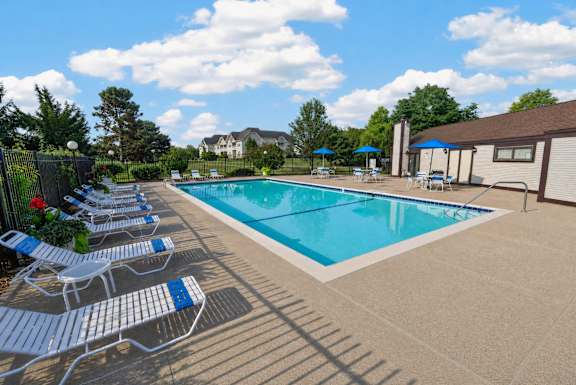 A pool surrounded by chairs and umbrellas.