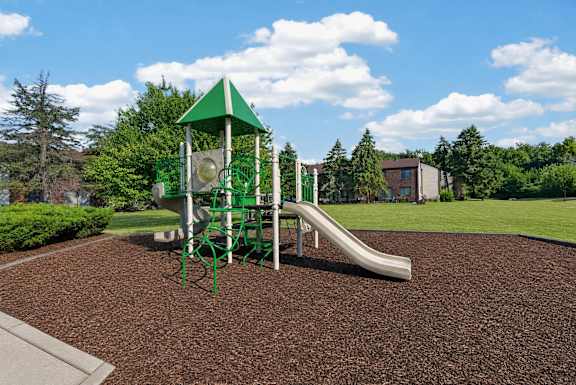 A playground with a green slide and a green and white tower.
