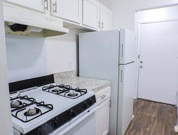 A white kitchen with a black stove top oven.