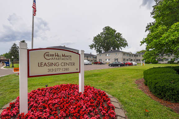 A leasing center sign for Cherry Hill Manor apartments is in front of a building.