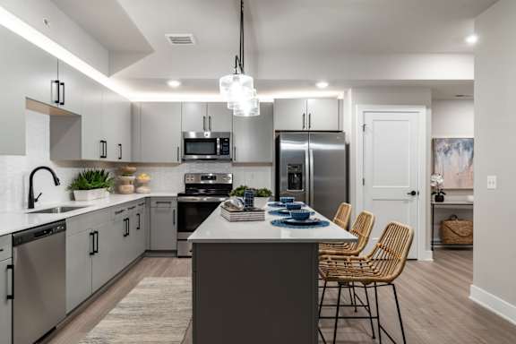 an open kitchen with stainless steel appliances and a large island with chairs