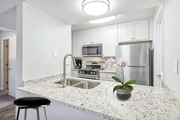 A kitchen with black countertops and white cabinets.