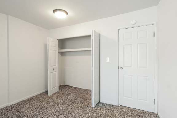 A white door is on the right side of a room with a carpeted floor.
