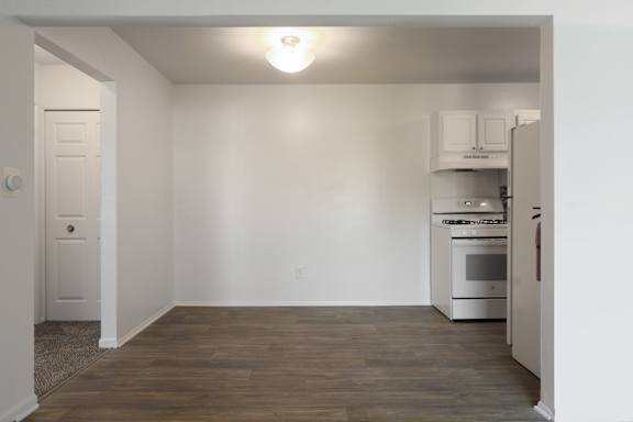 A kitchen with white cabinets and a wooden floor.