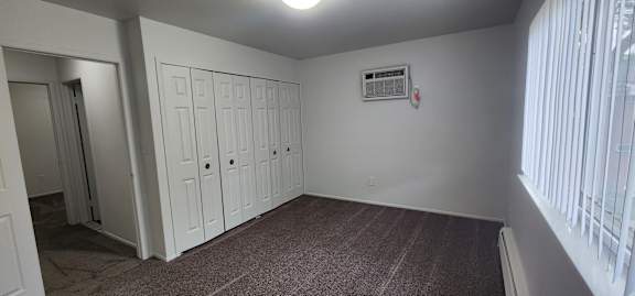 A room with white cupboards and a window with blinds.