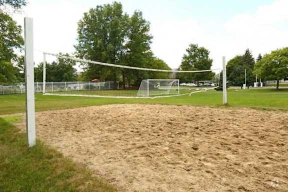 A sandy volleyball court with a net and goal post.