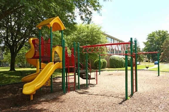 A playground with a yellow slide and red and green play structures.