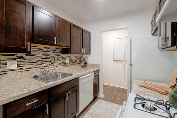 A kitchen with a white stove top oven and a white dishwasher.