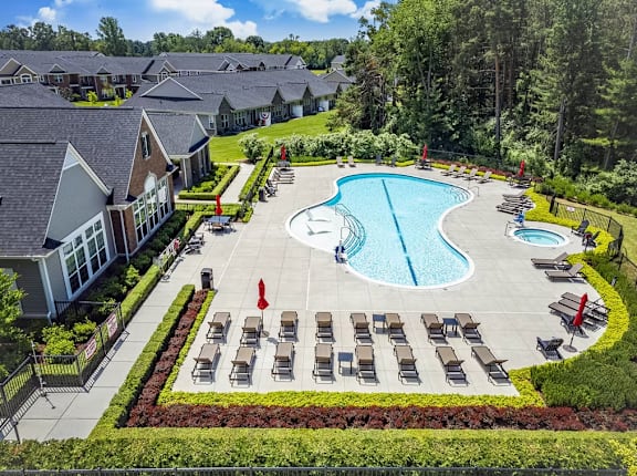 A large swimming pool surrounded by lounge chairs and trees.