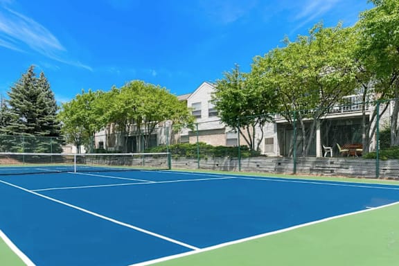 a tennis court in front of a building with trees