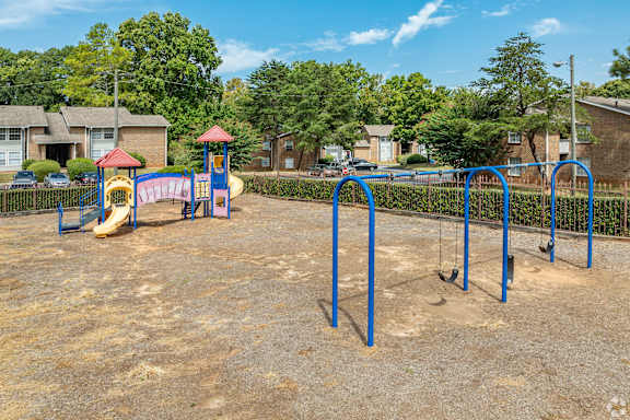A playground with a slide, swings, and a sandy area.