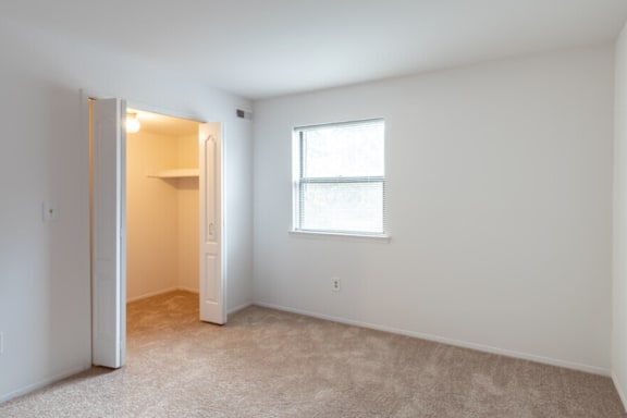 a bedroom with a door to a closet and a window