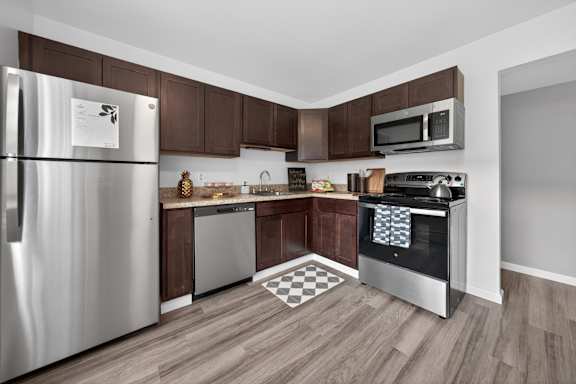 A kitchen with a stainless steel refrigerator, microwave, and oven.