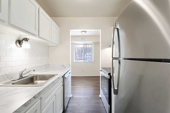A kitchen with white cabinets and a black fridge.