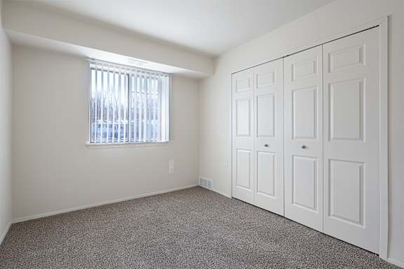 A room with a window and a set of white doors.