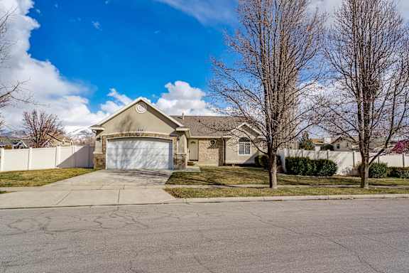 A house with a driveway and bare trees in front.