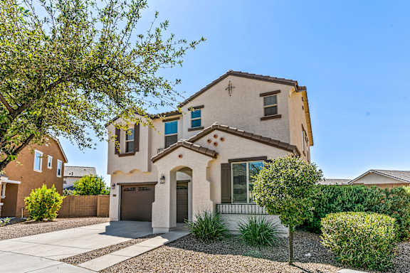 A house with a brown garage door and a tree in front.