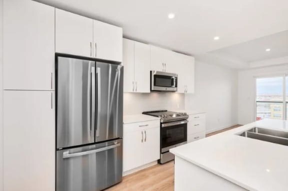 a white kitchen with stainless steel appliances and white cabinets