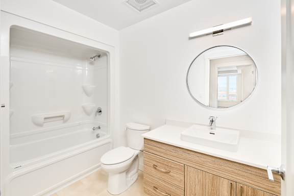 A white bathroom with a toilet, sink, and shower.