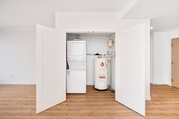 A white tank is in the middle of a room with a door open.