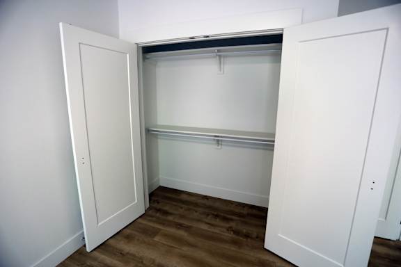 A white door is open to a room with a window and a wooden floor.