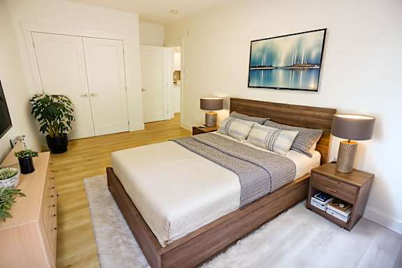 A bedroom with a large bed and a painting on the wall.