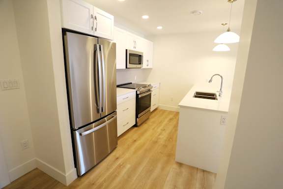 A kitchen with a refrigerator, microwave, oven, and sink.
