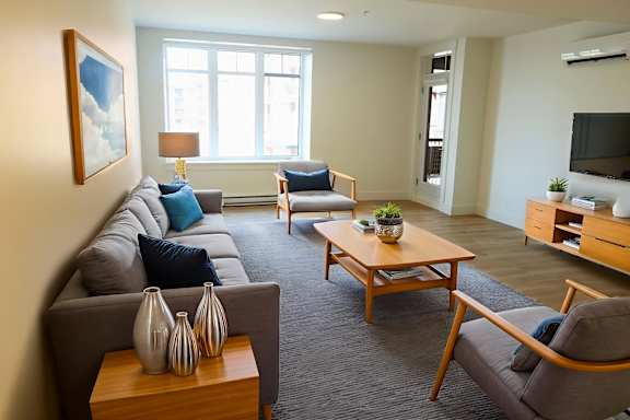 A living room with a grey couch, a wooden coffee table, and a painting on the wall.
