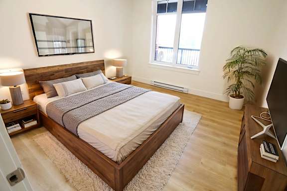 A bedroom with a large bed, a mirror, and a plant.