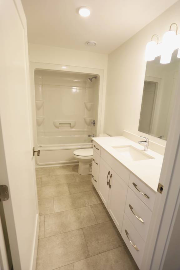 A white bathroom with a toilet, sink, and mirror.
