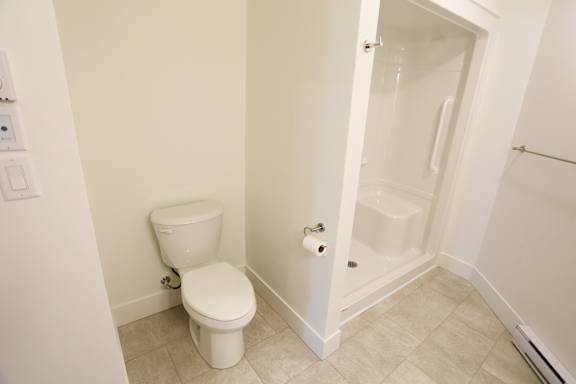 A white toilet in a small bathroom with a walk-in shower.