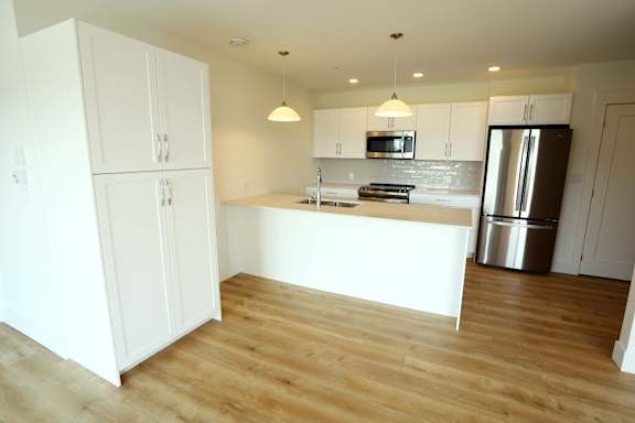 A kitchen with white cabinets and a wooden floor.