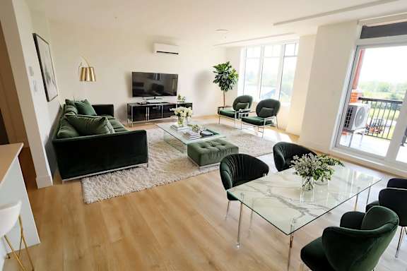 A living room with a glass table and green chairs.