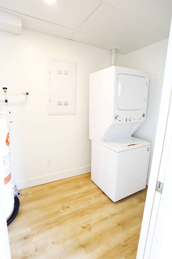A white tankless water heater in a room with wood flooring.