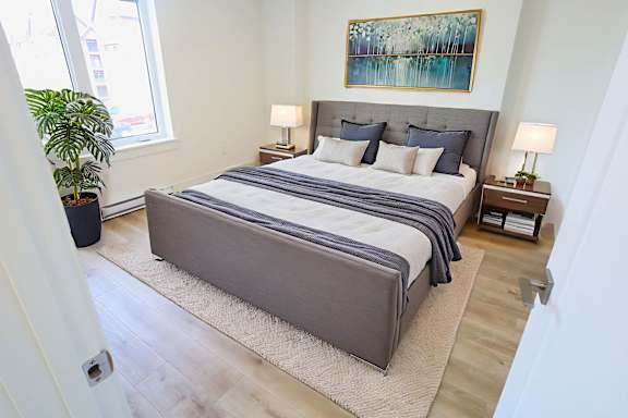 A bedroom with a large bed and a painting on the wall.