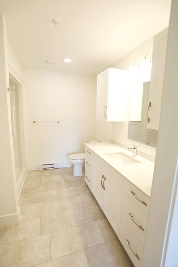 A white bathroom with a toilet, sink, and a mirror.