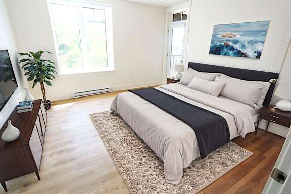 A bedroom with a large bed and a painting on the wall.