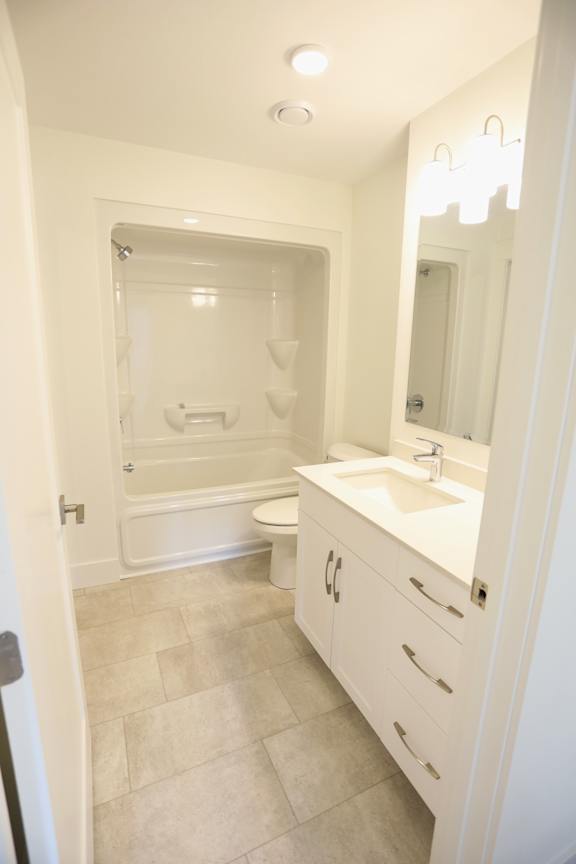 A white bathroom with a toilet, sink, and shower.