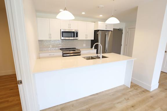 A kitchen with a white countertop and a microwave above it.