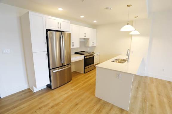 A kitchen with a refrigerator, microwave, and sink.