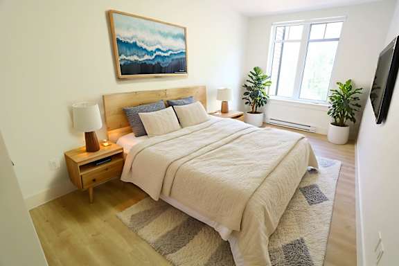 A bedroom with a large bed and a painting on the wall.